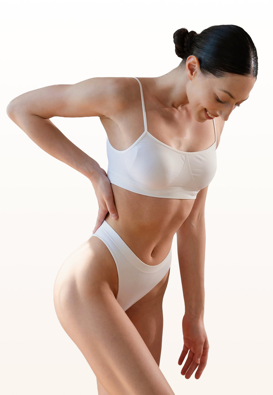Woman in white underwear leaning forward with a hand on her hip, representing labiaplasty