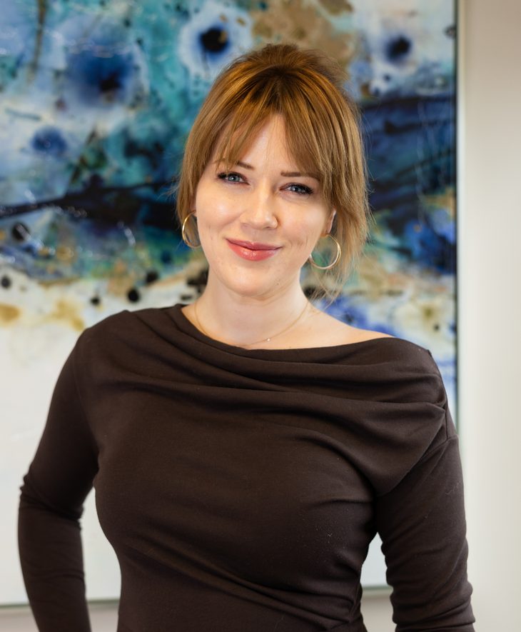 Anastasia Wooten, patient care coordinator, smiling in front of an abstract blue painting