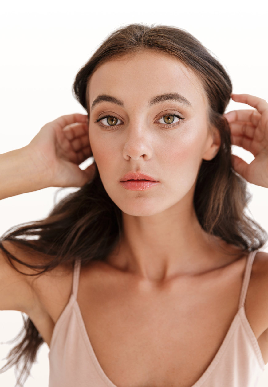 Young woman with full lips and smooth skin tucking her hair behind her ears