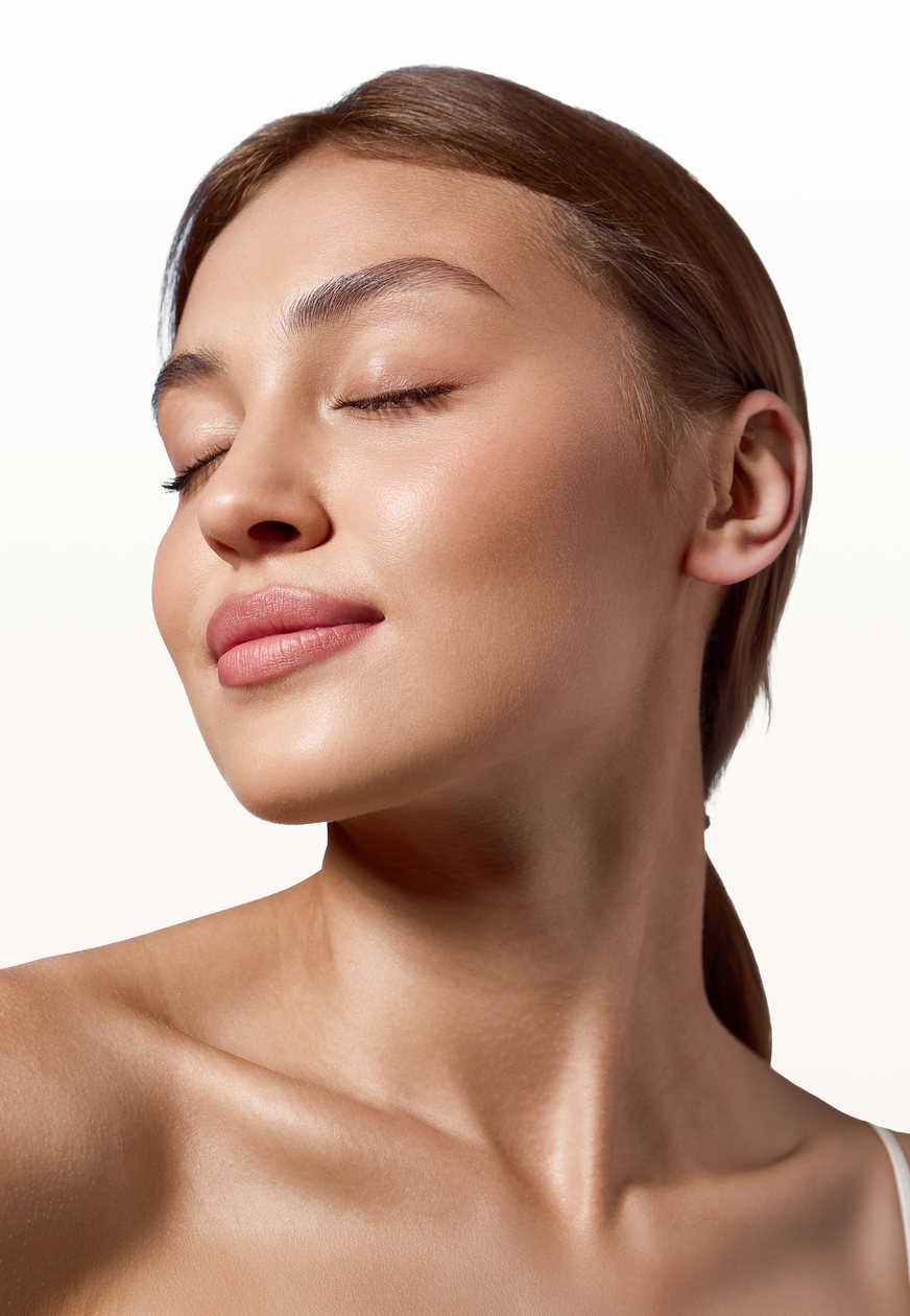 Woman with eyes closed showing firm, glowing skin along the jaw and neck