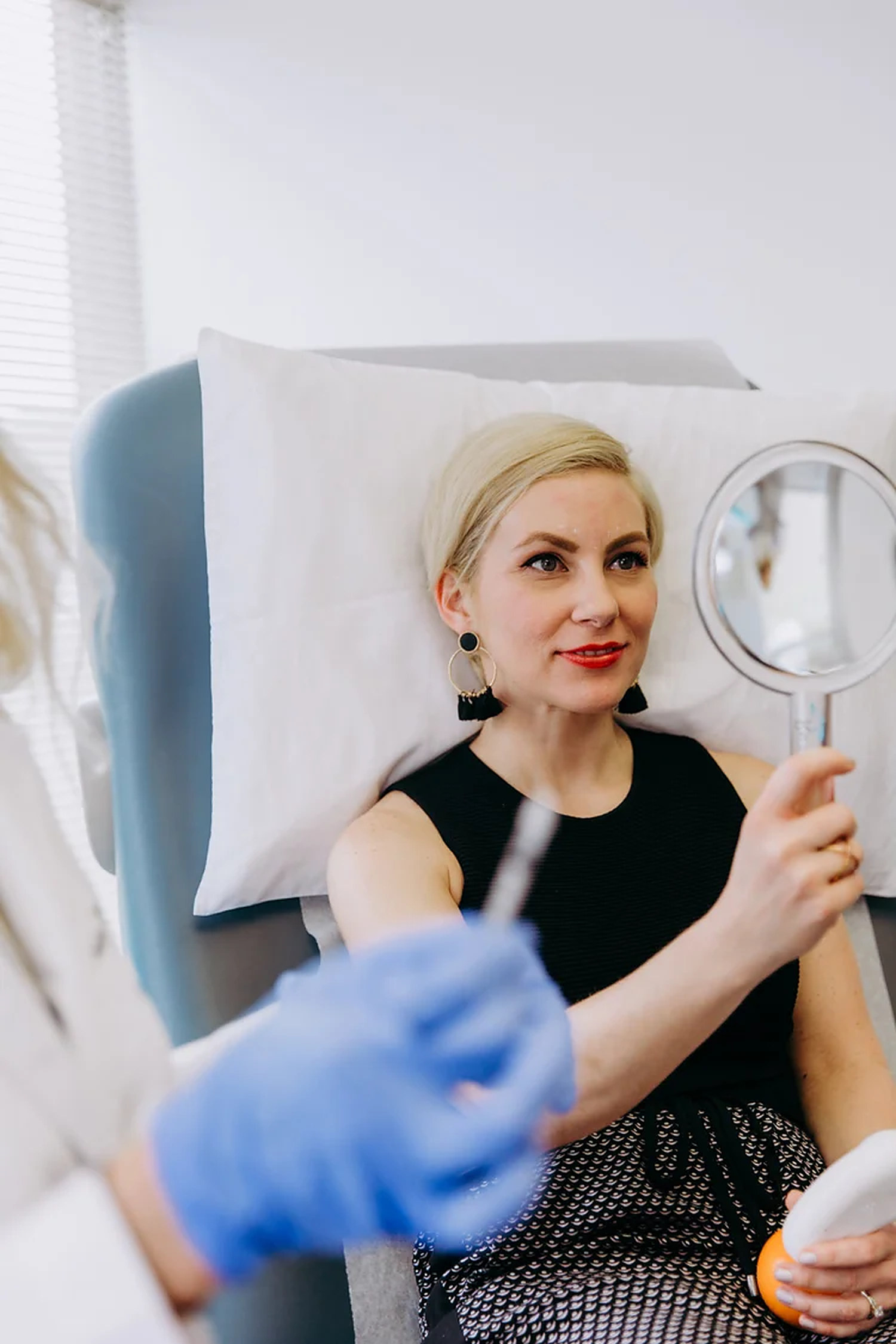 Smiling patient checking her results in a hand mirror during a treatment